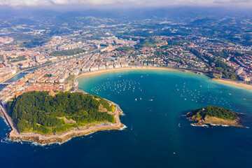 Picturesque aerial view of turquois water of La Concha Bay of San Sebastian with Santa Clara Island and moored pleasure yachts, Spain.. - obrazy, fototapety, plakaty