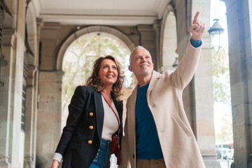 Happy mature couple having tourism walking outdoors in the city. Two adults enjoying a sightseeing walk on street. Houseband and wife in a honeymoon trip.