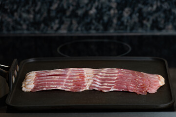 Close up of raw pork bacon on a skillet