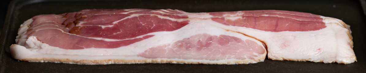 Fototapeta premium Close up of raw pork bacon on a skillet