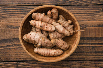 Wooden bowl of curcuma roots. Turmeric spice. Top view, flat lay.