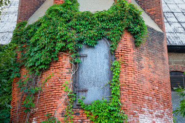 Iron Door and Ivy at Base of an Industrial Brick Chimney - 681268618