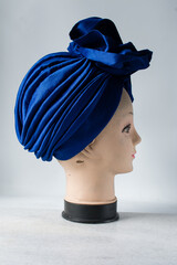 Blue turban on a mannequin head, pleated blue fashion turban on a white background