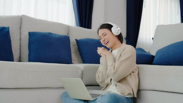 Funny euphoric young asian woman celebrating winning or getting ecommerce shopping offer on computer laptop. Excited happy girl winner looking at laptop celebrating success