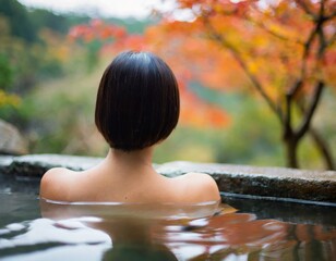 紅葉の美しい温泉に浸かっている日本人女性の後ろ姿