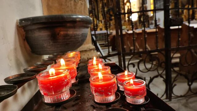 Burning candles in a church building.Catholic faith symbols. 4k footage