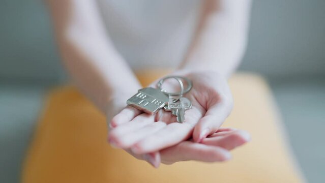 Happy Asian woman holding house keys on house shaped keychain concept for buying a new home