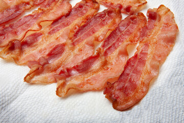 Studio close up of cooked bacon on dish and paper towel.