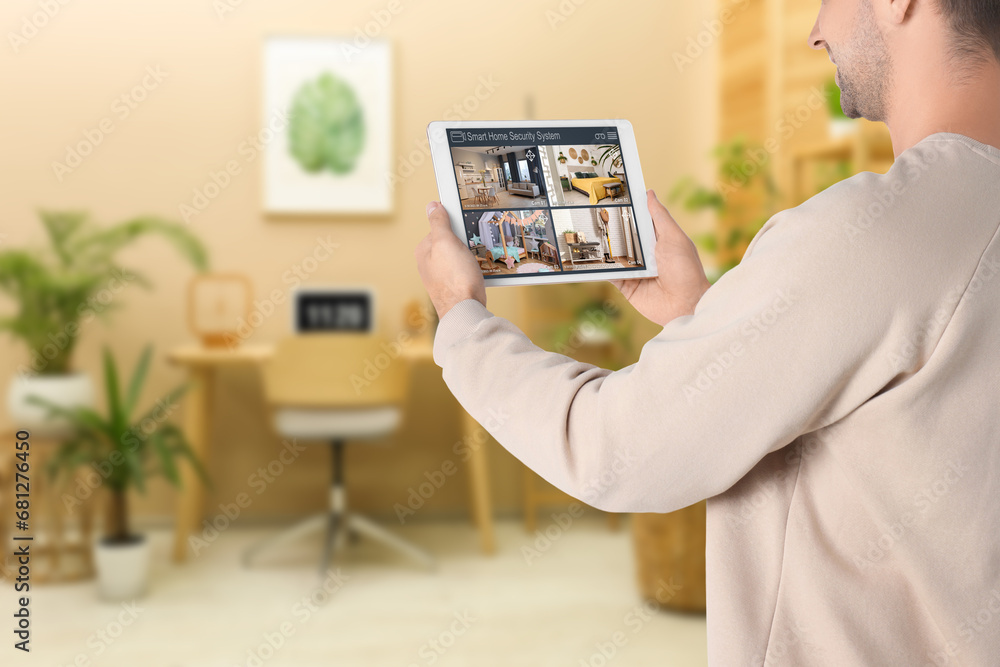 Poster man using smart home security system on tablet computer indoors, closeup. device showing different r
