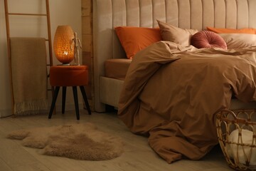 Bed with brown linens in cozy bedroom. Interior design