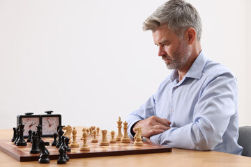 Man playing chess during tournament at table against white background