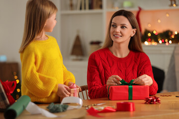 Christmas presents wrapping. Mother and her little daughter decorating gift boxes at home, selective focus - Powered by Adobe