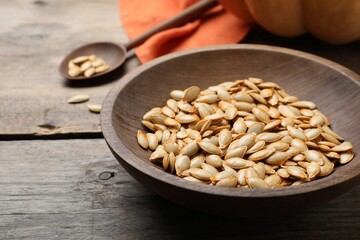 Raw pumpkin seeds on wooden table, closeup