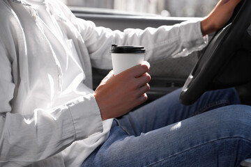 Coffee to go. Man with paper cup of drink driving his car, closeup
