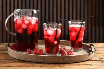 Delicious iced hibiscus tea and dry flowers on wooden table
