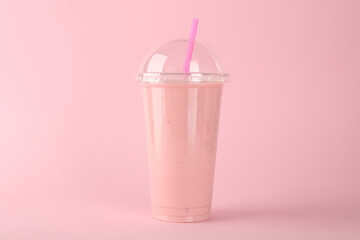 Plastic cup of tasty smoothie on pink background