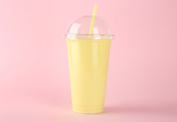 Plastic cup of tasty smoothie on pink background