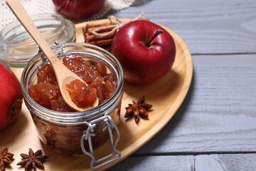Delicious apple jam in jar, fresh fruits and spices on grey wooden table. Space for text