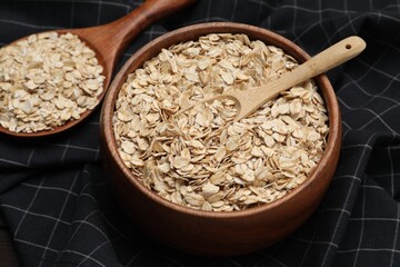 Bowl with scoop and spoon of oatmeal on table, closeup