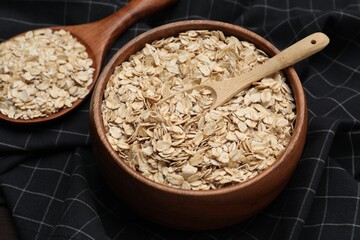 Bowl with scoop and spoon of oatmeal on table, closeup
