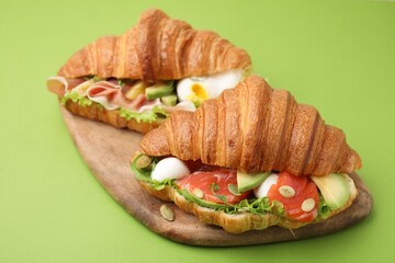Delicious croissants with prosciutto and salmon on green table
