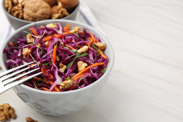 Tasty salad with red cabbage and walnuts on white wooden table, closeup. Space for text