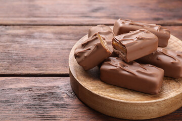 Tasty chocolate bars with nougat on wooden table, space for text