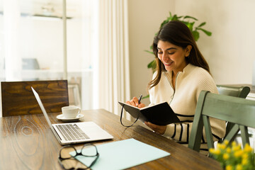 Hispanic woman doing remote work on the laptop looking happy