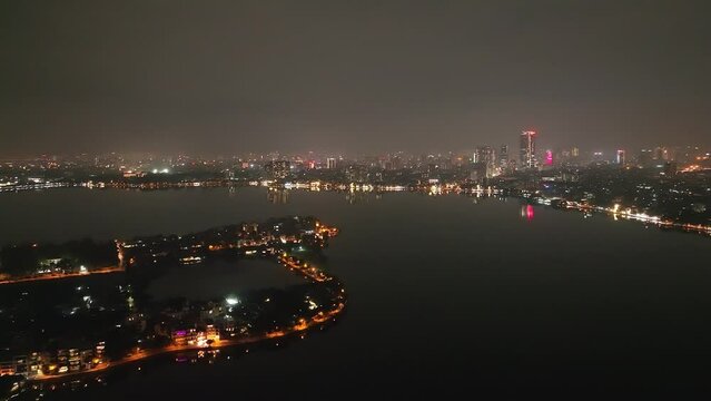 Dark still city night skyline and lake with atmospheric haze in distance