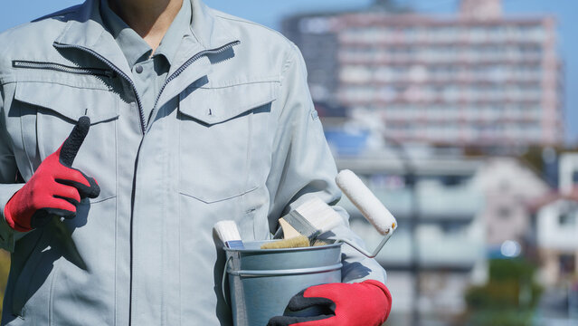  塗装道具を持つ作業服の男性｜リフォーム・塗装業者イメージ