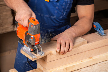A carpenter using a jigsaw to cut wood cuts bars.
