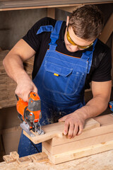 A carpenter using a jigsaw to cut wood cuts bars. Home repair concepts, close up.