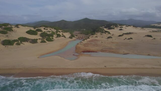 Spiaggia di Piscinas, Sardinia: flying from the sea towards the shore of the beach and seeing the canals that connect sea and land.