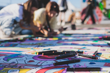 Process of drawing on asphalt and pavement, kids and children with crayons, chalk and markers, teens creating street art on the ground, graffiti and pictures on sideways, street painting festival - Powered by Adobe