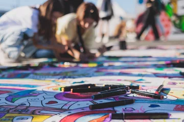 Foto auf Acrylglas Process of drawing on asphalt and pavement, kids and children with crayons, chalk and markers, teens creating street art on the ground, graffiti and pictures on sideways, street painting festival © tsuguliev