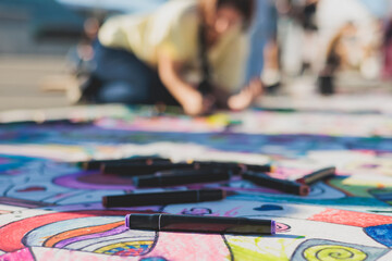 Process of drawing on asphalt and pavement, kids and children with crayons, chalk and markers, teens creating street art on the ground, graffiti and pictures on sideways, street painting festival