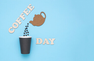 A figurine of a teapot with pouring grains and the inscription coffee day on blue.