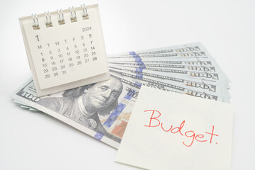 BUDGET text on paper, US dollar with 2024 JAN calendar on a white background. Finance, money...