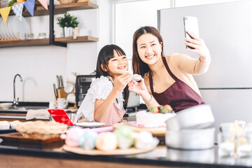 Obraz na płótnie Canvas Happy asian family mother and daughter cooking in kitchen selfie with smartphone for social media