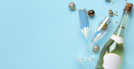 Bottle of champagne, glasses and Christmas balls on light blue background with space for text