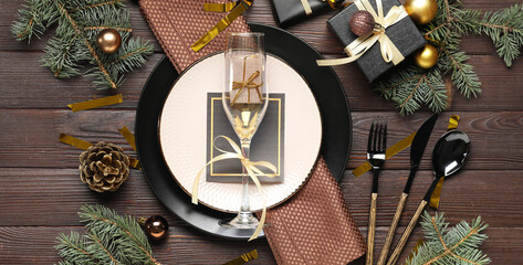 Beautiful table setting with champagne glass, Christmas gifts and decorations on brown wooden...