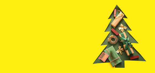 Hole in yellow paper in shape of Christmas tree and many decorations. Banner for design