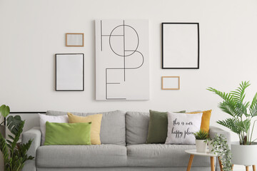 Interior of living room with cozy sofa, paintings and houseplants