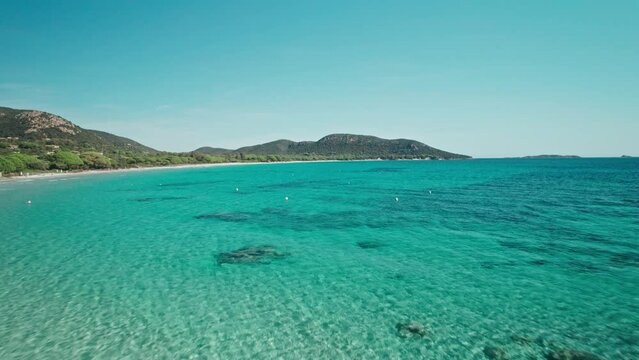 Drone flying through trees at a beach with turquoise water, Corsica, France