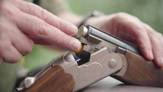 Double-barrelled shotgun cocked open being loaded with shells. Handheld