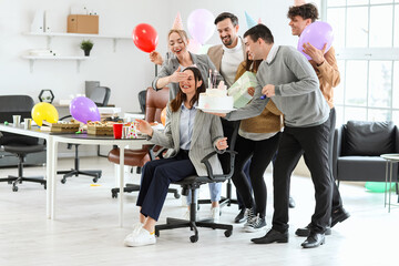 Group of business people surprising their colleague with Birthday cake at party in office