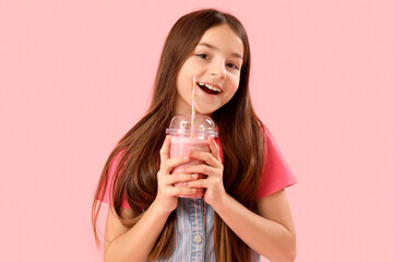 Little girl with glass of smoothie on pink background