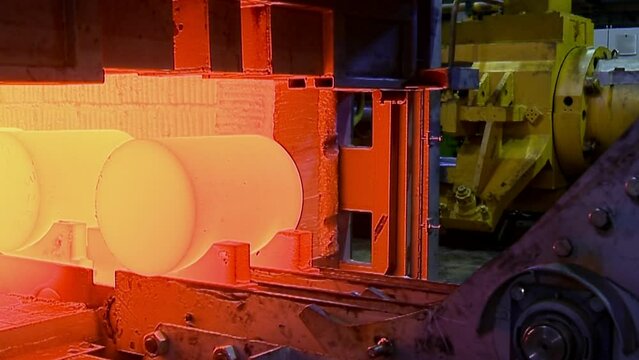 Pipe Production Line in Metal Factory. Hot Metal Tubes comes from the industrial Oven. Factory Furnace. Conveyor belt at Non-Ferrous Metal Production. Industrial Line. Hot Red Copper and Brass Bars.
