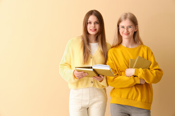 Fototapeta premium Happy female students books on pale yellow background