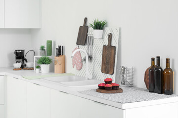 White kitchen counters with cutting boards, pegboard, sink and utensils